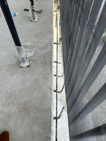 Exposed corroded rebar along a concrete balcony edge in Key West showing active spalling damage