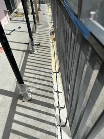 Full-length concrete walkway showing extensive spalling repair needed along railing edge in Florida Keys